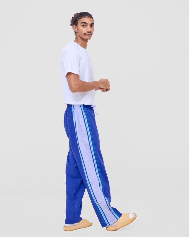 Person wearing a white t-shirt and blue pants with white stripes on a light gray background