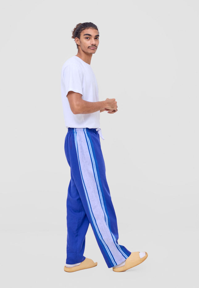 Person wearing a white t-shirt and blue pants with white stripes on a light gray background